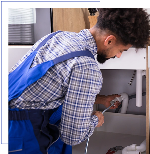 Woman Looking At Male Plumber Cleaning Clogged Pipes