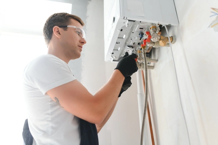 Professional plumber checking a boiler and pipes, boiler service concept.