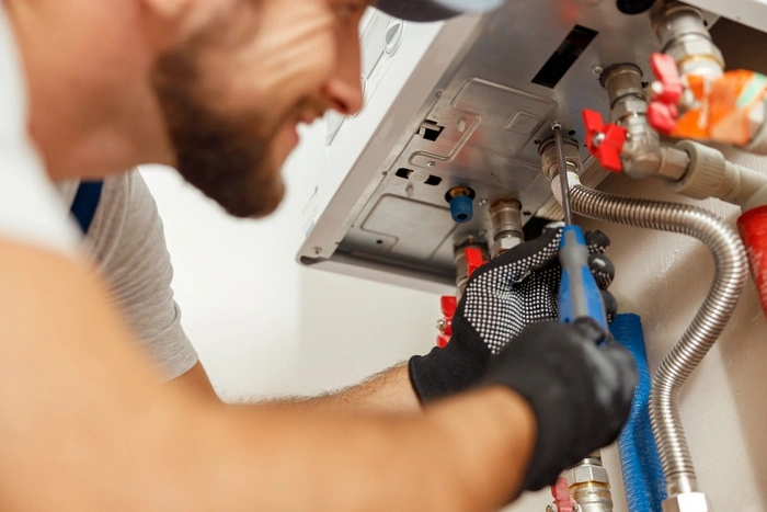 Closeup of plumber using screwdriver while installing new steel hot water central heating system in apartment