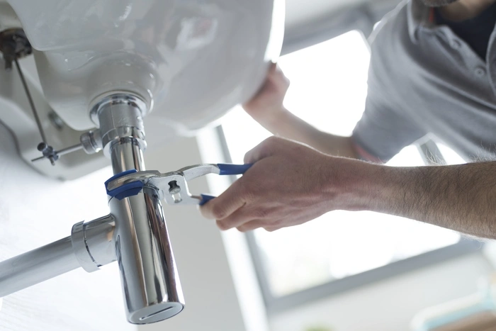 Professional plumber fixing a leaking bathroom sink, he is using water pump pliers